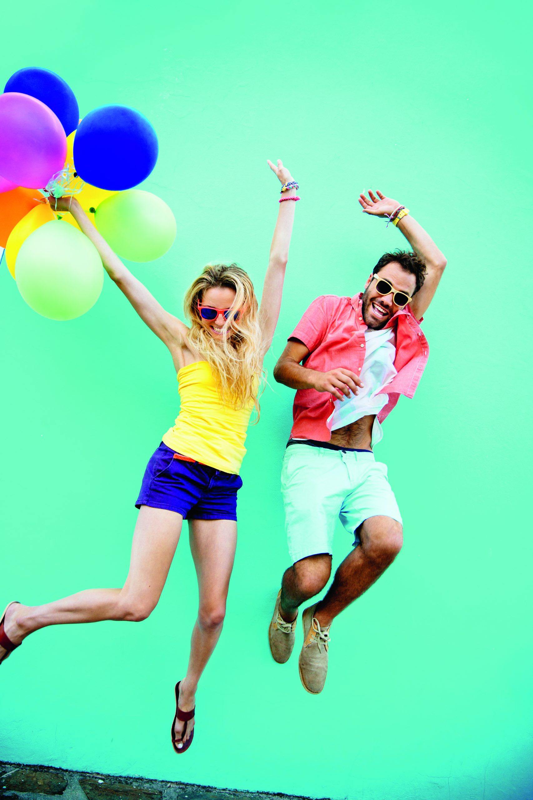 Young couple jumping with joy colorful balloons